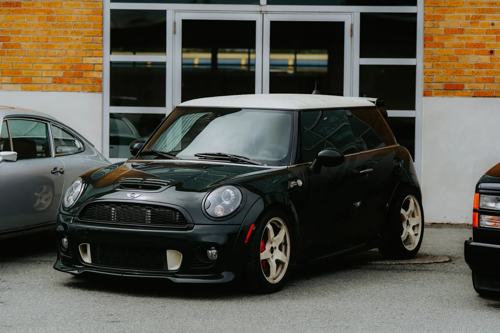 Černé MINI Cooper s bílou střechou zaparkované u budovy