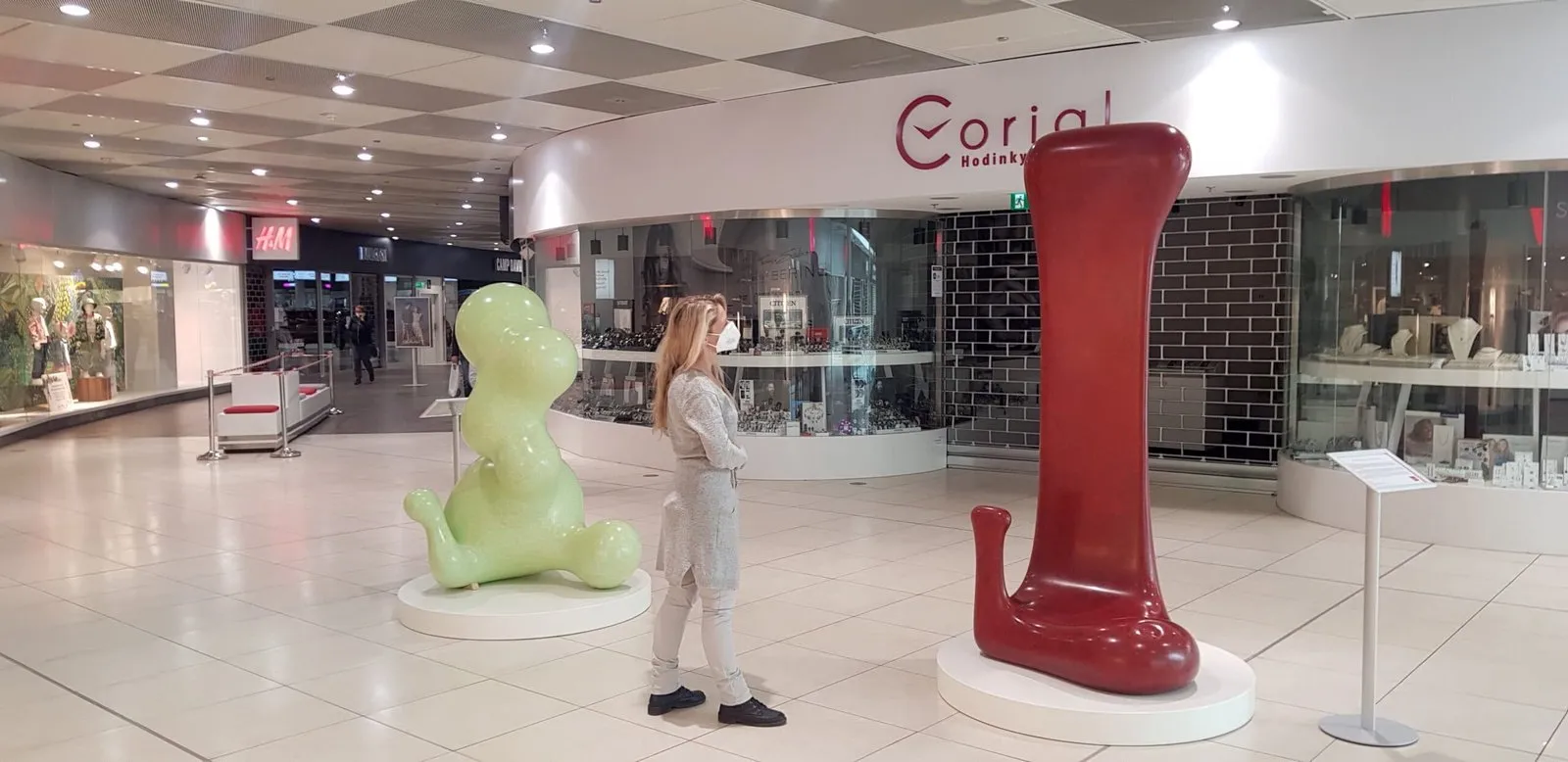 Žena obdivuje dvě moderní sochy v obchodním centru.