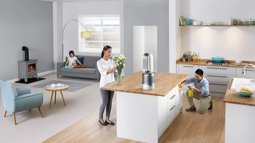 Moderní domácnost s topidlem Dyson, ženou s květinami a mužem při údržbě.