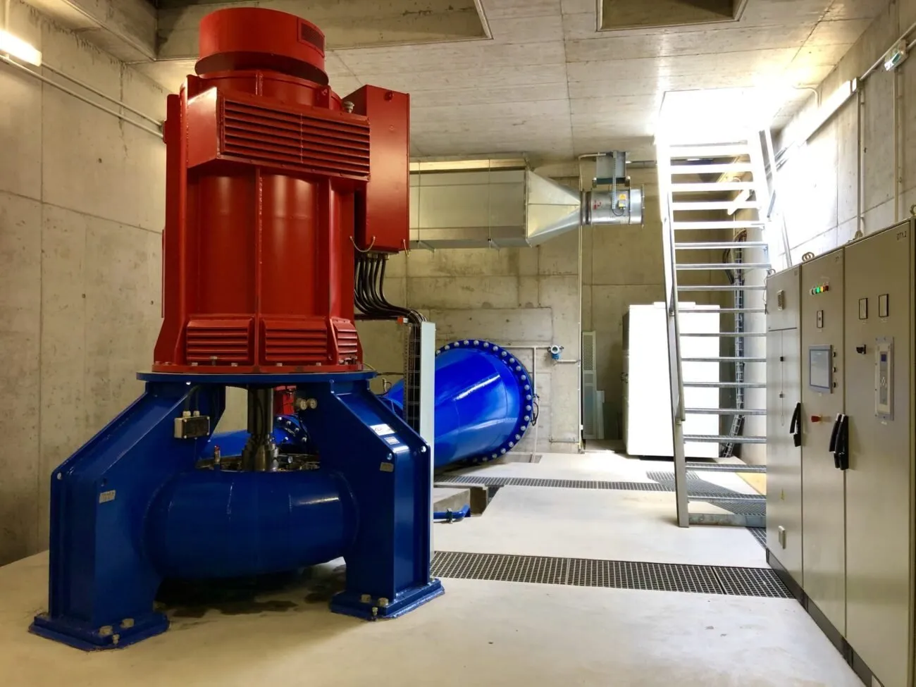 Speciální hydroelektrická turbína a modré potrubí v interiéru elektrárny.