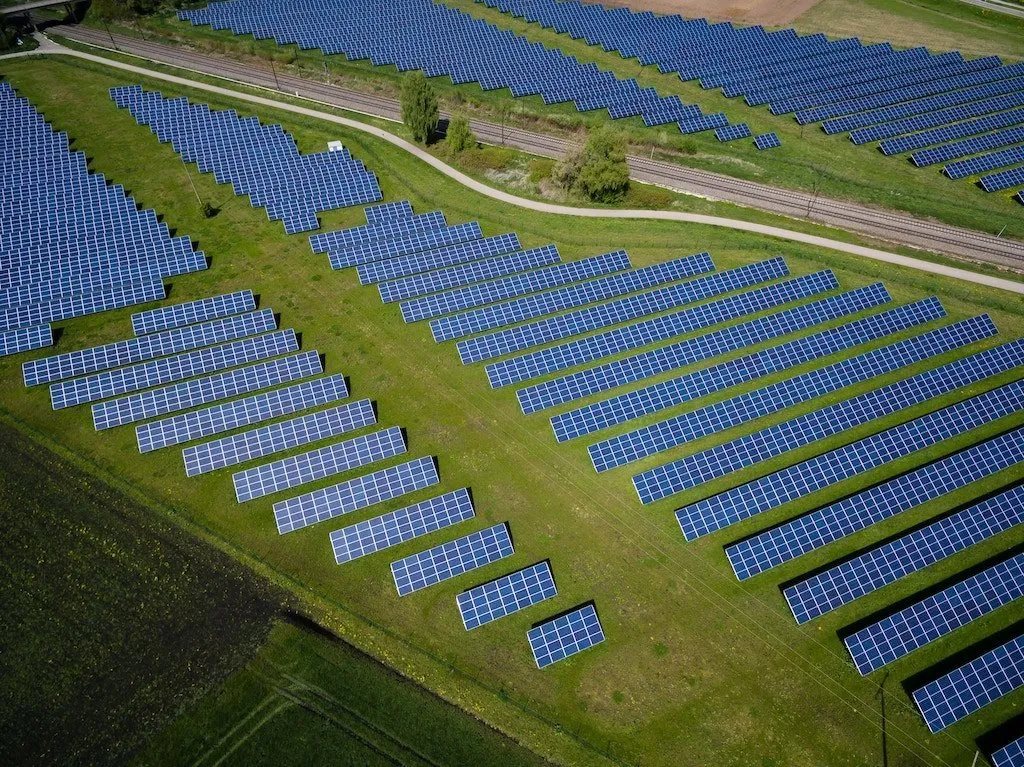 Rozsáhlé solární panely na zeleném poli, známka obnovitelné energetiky.