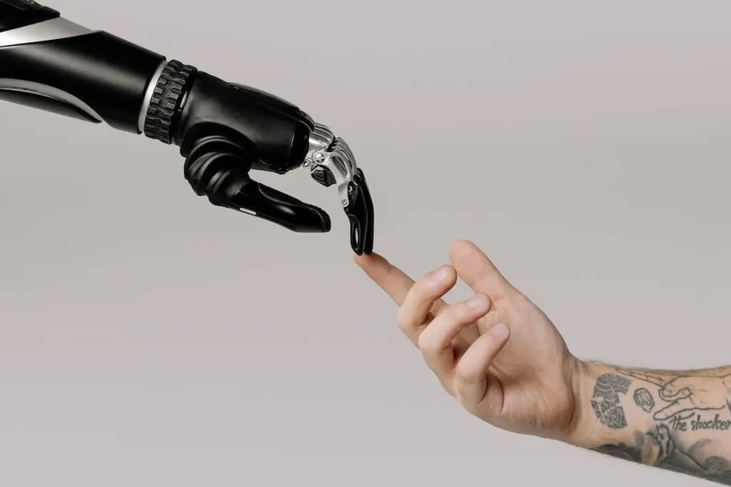 Ruka robota se dotýká lidské ruky, symbolizující technologickou spolupráci.