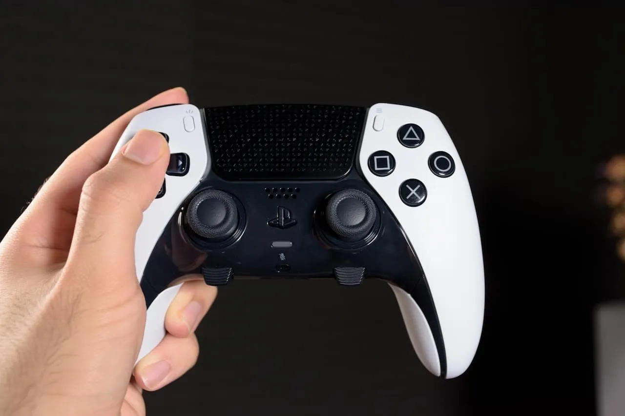 Hráč drží bílý ovladač konzole PlayStation 5.