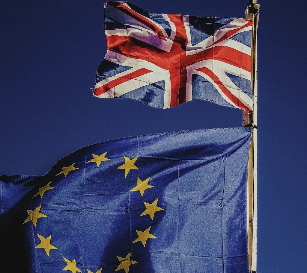 Britské a evropské vlajky vedle sebe na modré obloze.