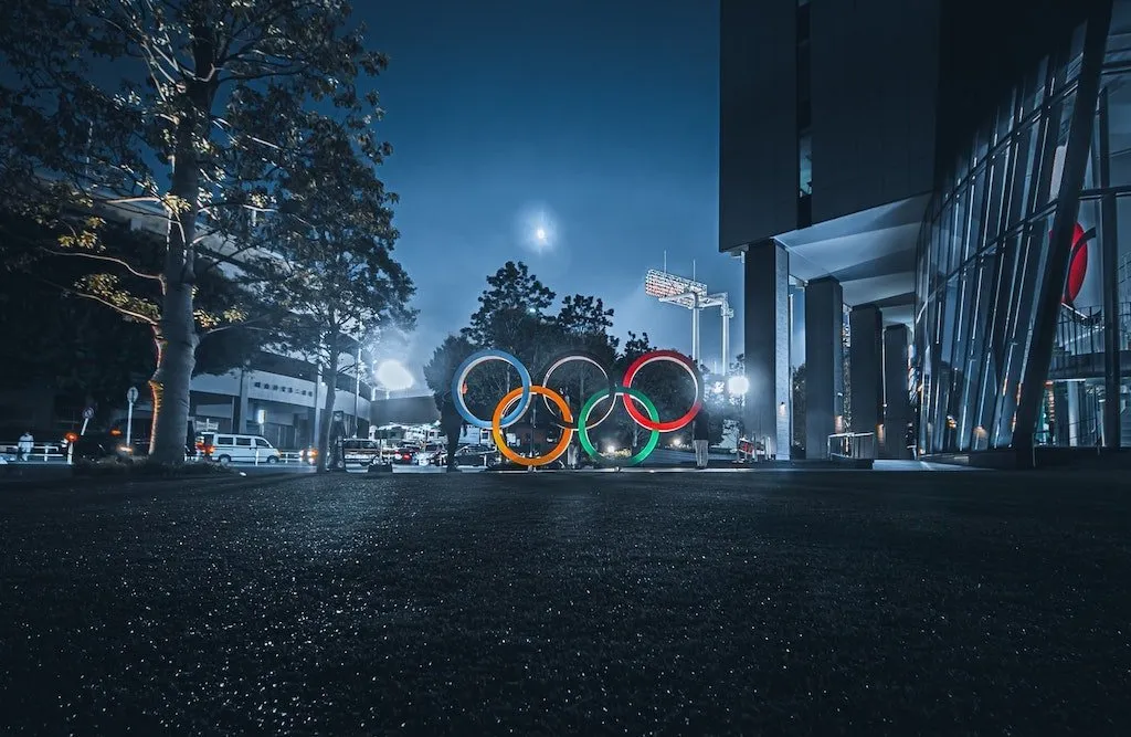 Olympijské kruhy osvětlené v noci před budovou v Tokiu.