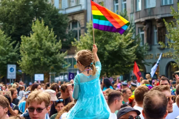 Duha nad hlavami účastníků Prague Pride 2025 – Pride vlajka vlající v ulicích Prahy jako symbol rovnosti, diverzity a podpory LGBTQ+ komunity.